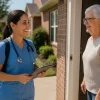 Nurse in blue scrubs visiting a smiling senior woman at her front door for affordable home care for senior