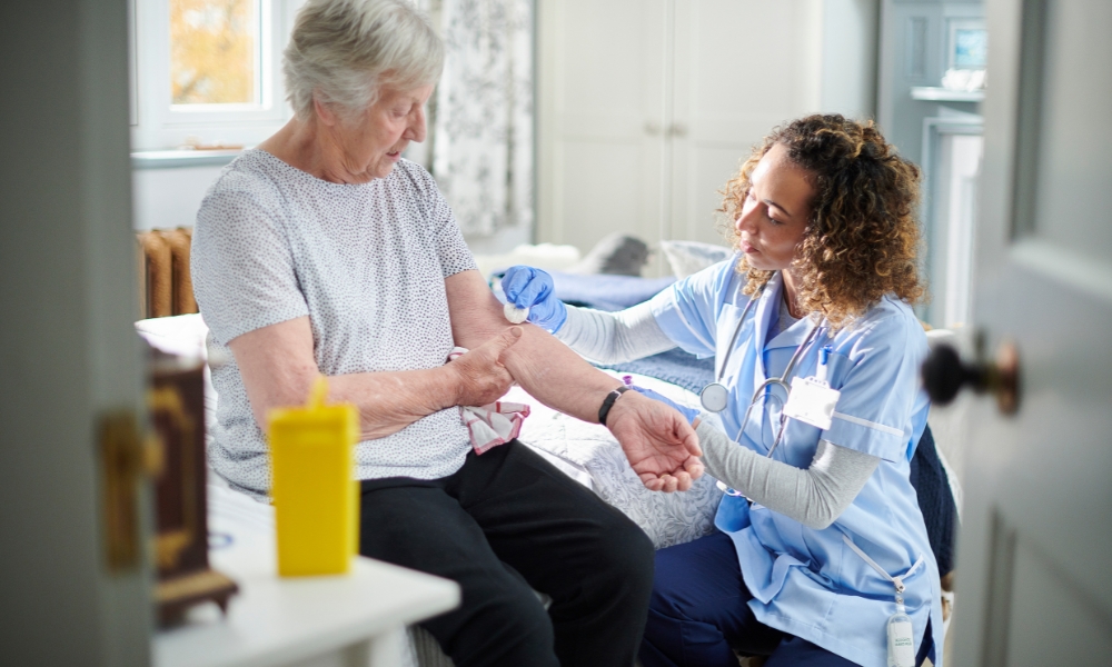 Skilled nurse helping diabetes patient with foot care and health monitoring at home