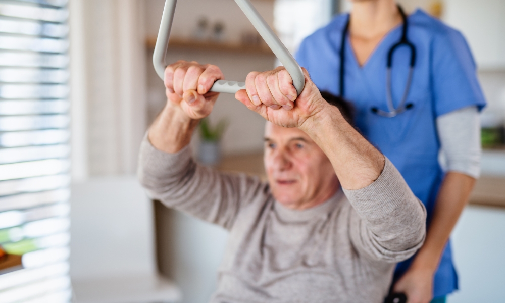 Physical therapist helping senior patient exercise at home during rehabilitation session